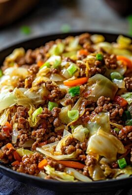 Close-up of Chinese ground beef stir fry with cabbage, carrots, and green onions in a black bowl