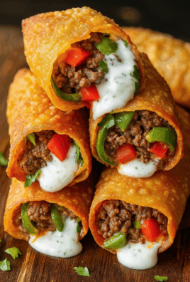Golden crispy nacho egg rolls filled with seasoned beef, peppers, and cheese, topped with creamy ranch sauce