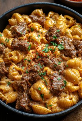 Close-up of creamy pasta shells with tender steak pieces and a paprika cheese sauce, garnished with parsley
