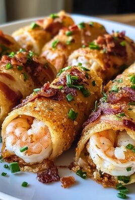 Close-up of crispy shrimp egg roll bombs wrapped in bacon, garnished with chopped chives on a white plate