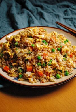 A plate of egg fried rice with peas, carrots, and scrambled eggs