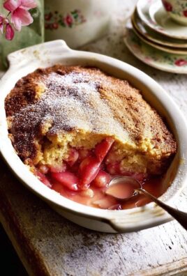 Warm rhubarb pudding cake in a baking dish with golden top and juicy pink rhubarb filling