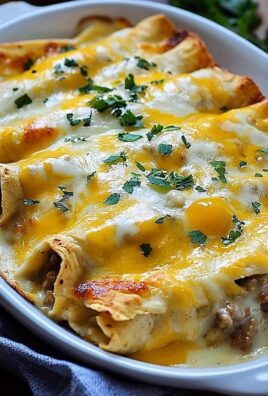 Close-up of cheesy baked beef enchiladas topped with melted cheddar and parsley in a white casserole dish