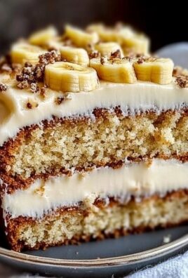 Close-up of banana bread cake layered with cream cheese frosting and topped with sliced bananas and crunchy crumble