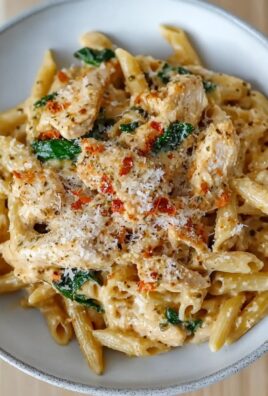 Close-up of creamy chicken penne pasta topped with parmesan, herbs, and red pepper flakes