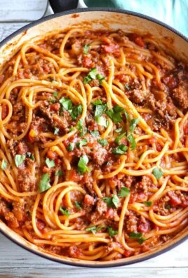 Top view of cowboy spaghetti with beef, tomato sauce, and parsley in a skillet