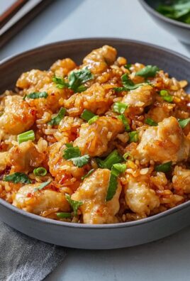 Close-up of Bang Bang chicken fried rice in a dark bowl garnished with green onions and cilantro