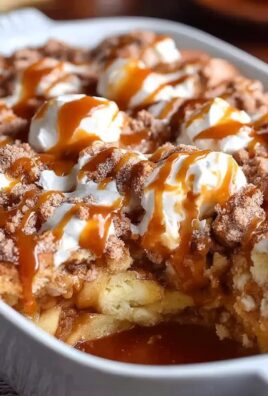 Warm caramel apple cobbler with whipped cream and caramel drizzle in a white baking dish