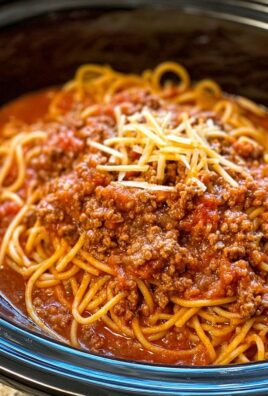 Close-up of hearty spaghetti with ground beef sauce in a slow cooker, topped with shredded cheese