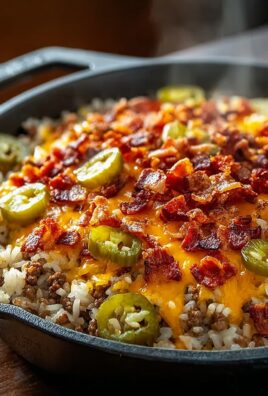 Skillet filled with cheesy rice topped with ground beef, crispy bacon, jalapeños, and melted cheddar cheese.