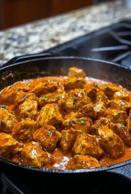 Creamy paprika chicken pieces in a cast iron skillet simmered in rich red sauce