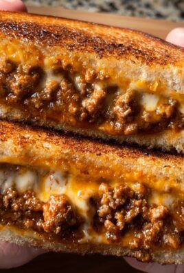 Close-up of a gooey sloppy joe grilled cheese sandwich with melted cheese and savory meat filling